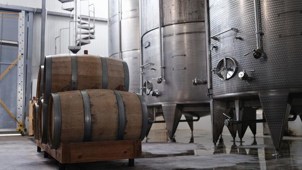 Huge tanks in wine cellars and wooden barrels of wine or alcohol. Production of elite collection wine concept