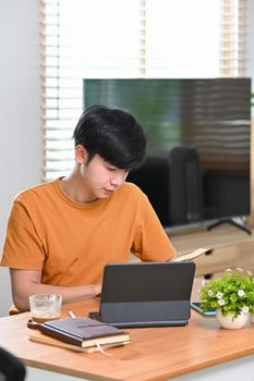 Young man reading book while sitting in living room.