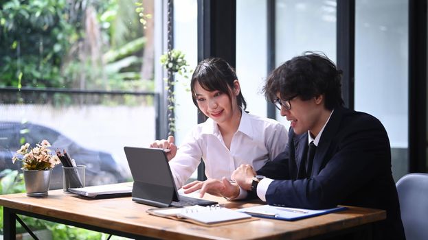 Two young business colleagues analyzing information on computer tablet together.