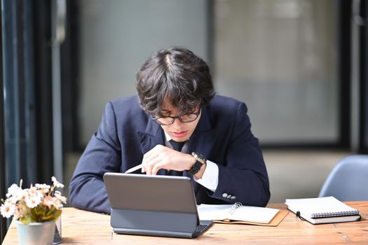 Young businessman working with computer tablet in bright office.