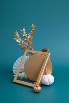 Still life of gold and white elements on a turquoise background. Minimalistic autumn concept.