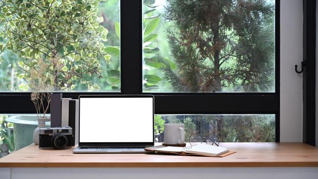 Home office desk with laptop computer, coffee cup and books.