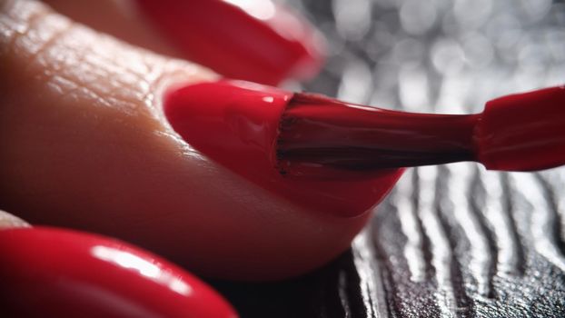 Red nail polish is applied to hand. Beautiful manicure process concept
