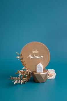 Hello Autumn inscription with still life of gold and white decorative elements and leaves on a turquoise background. Creative autumn concept