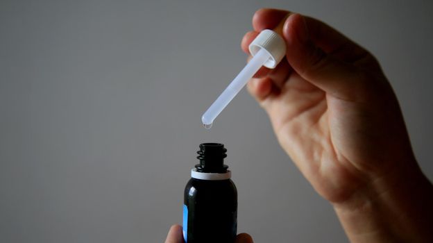 salvador, bahia / brazil - may 7, 2020: hand removes weak medication with the aid of a dropper.