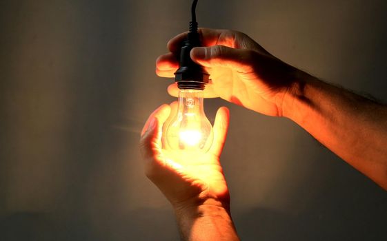 salvador, bahia / brazil - may 17, 2020: hands hold incandescent lamp lit in residence in the city of Salvador.
