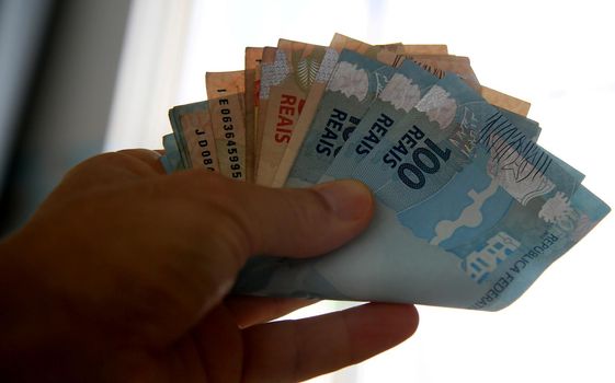 salvador, bahia / brazil - march 28, 2020: woman's hands hold reais banknotes, currency used in Brazil.