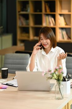 Pretty young entrepreneur having phone conversation, negotiations with business partner on mobile phone.