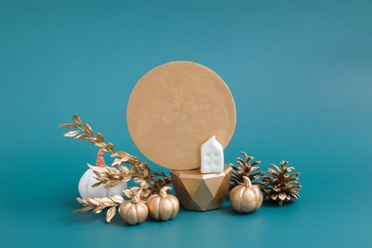 Still life of gold and white pumpkins, acorns and a house on a turquoise background. Minimalistic autumn concept with copy space