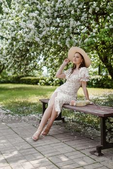 An attractive long-haired woman walks in the spring in the park of blooming apple trees. Spring portrait of a woman