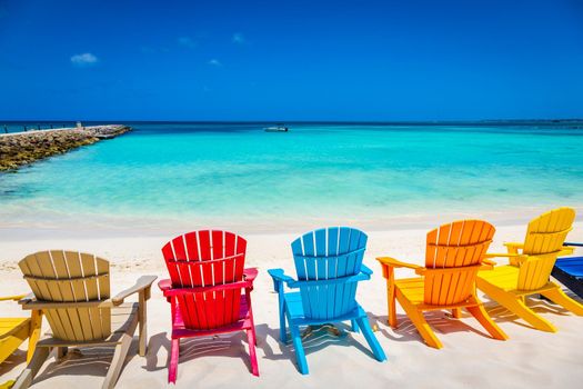 Idyllic beach with rustic wooden adirondack chairs in Aruba, Dutch Antilles