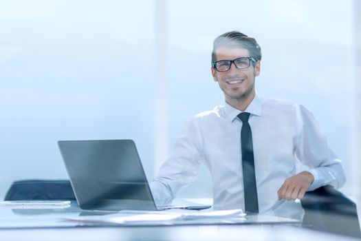 smiling young businessman sitting in a spacious office.photo with copy space