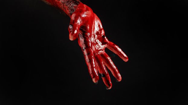 Close-up of a male hand stained with blood on a black background