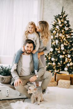 Happy family: mom, dad and pet. Family in a bright New Year's interior with a Christmas tree.