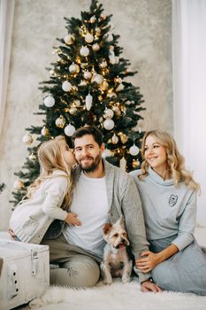 Happy family: mom, dad and pet. Family in a bright New Year's interior with a Christmas tree.