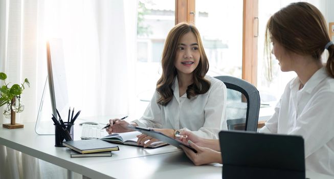 Two young Asian businesswoman discuss investment project working and planning strategy. Business people talking together with laptop computer at office..