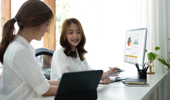 Two young Asian businesswoman discuss investment project working and planning strategy. Business people talking together with laptop computer at office..