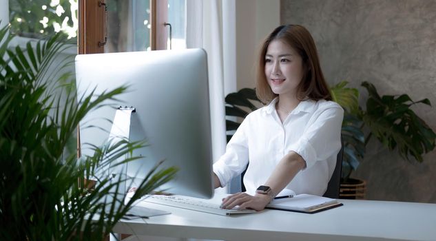 Charming asian businesswoman sitting working on laptop in office..