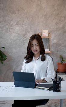 Charming asian businesswoman sitting working on laptop in office..