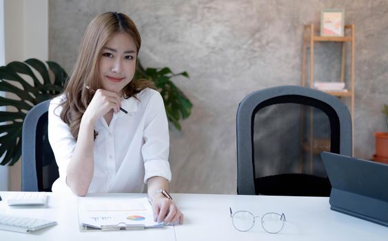 Charming Asian woman working at the office using a laptop Looking at the camera..