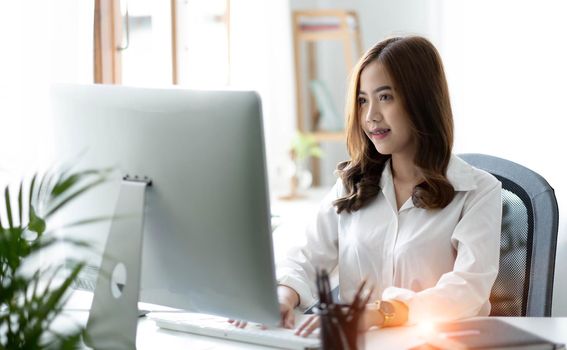 Beautiful young asian woman sitting at coffee shop using laptop. Happy young businesswoman sitting at table in cafe with tab top computer..