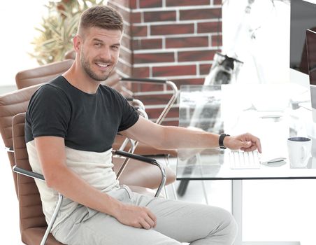 confident young designer sitting at his workplace in office