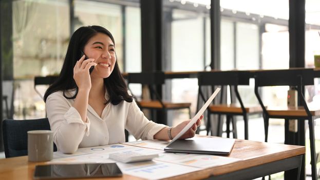 Smiling young businesswoman having pleasant conversation, negotiations with business partner on mobile phone.