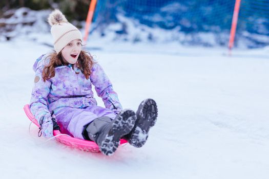 A young girl tobogganing at Lake Mountain on a clear sunny day in Victoria, Australia