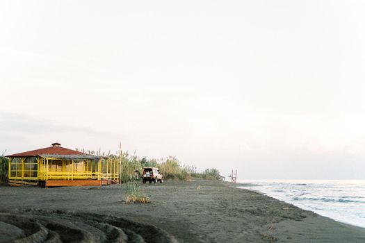 Car stands near a wooden house on the beach by the sea. High quality photo