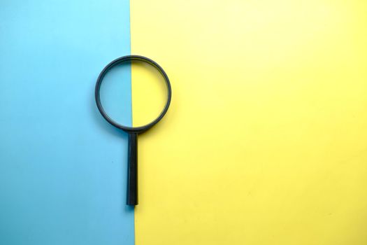 a magnifying glass on color background top view .