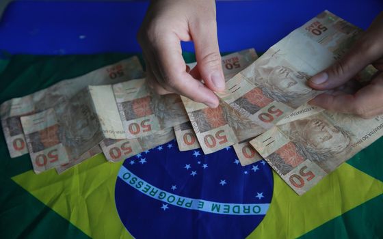 salvador, bahia, brazil - april 3, 2022: fifty reais banknotes next to a brazil flag.