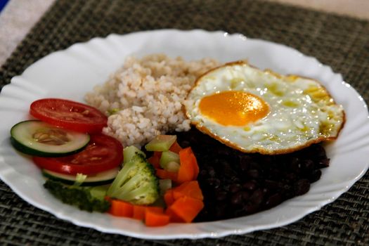 salvador, bahia, brazil - june 3, 2022: food plate with black beans, rice salad and fried egg.