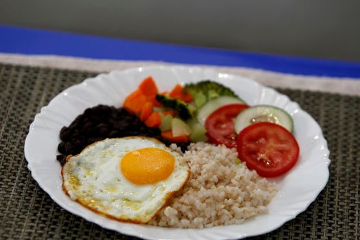 salvador, bahia, brazil - june 3, 2022: food plate with black beans, rice salad and fried egg.