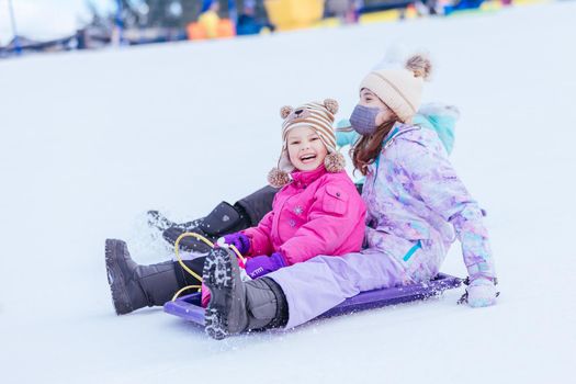 Young girls tobogganing at Lake Mountain on a clear sunny day in Victoria, Australia