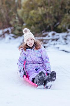 A young girl tobogganing at Lake Mountain on a clear sunny day in Victoria, Australia