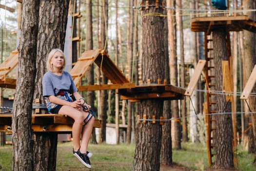A girl passes an obstacle in a rope town. A girl in a forest rope park.