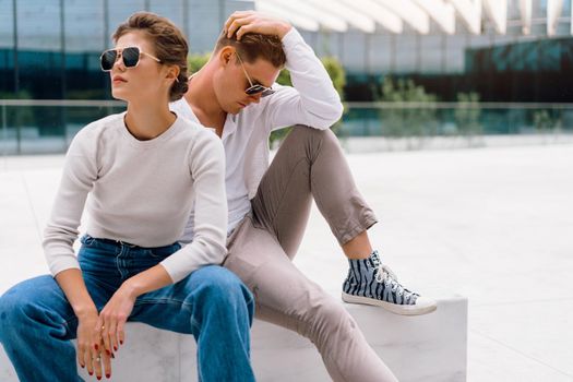 Young couple having problems in their relationship. man and woman friends in sunglasses sitting bench in city unhappy emotions. Relationships problem.