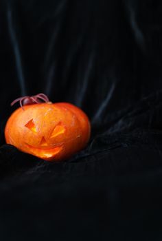 October 31, Halloween - Old Jack-o-Lantern on a black background. The spider sits on a pumpkin. Place for an inscription