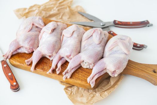 Raw quails lie on a wooden board. Preparation for cutting diet lean meat