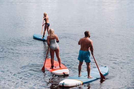 The family spends time together swimming on sup boards on the lake.