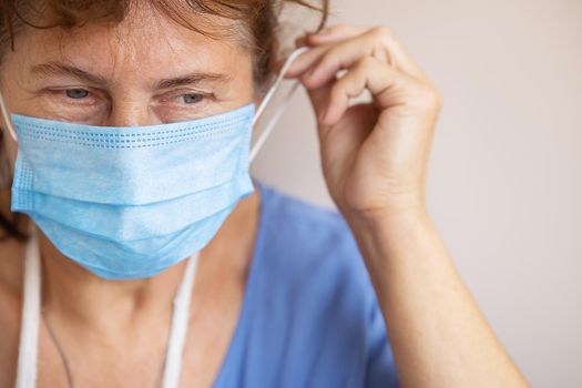 Doctor or nurse taking off her medical mask, portrait, close up, white background, copy space