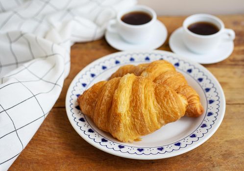 Breakfast in bed, fresh croissants and a cup of coffee on a wooden tray. Fine morning