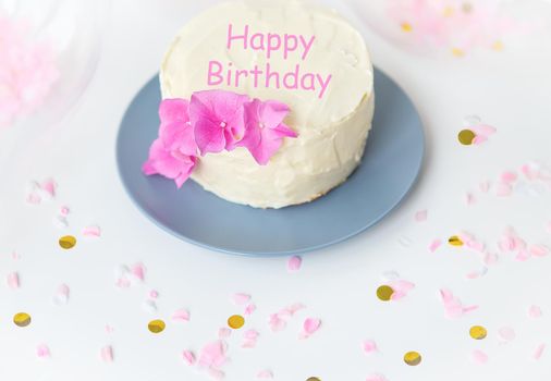 Very beautiful small white bento cake, decorated with fresh flowers of pink hydrangeas. Happy birthday lettering