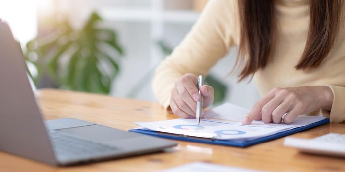 Business woman calculating domestic expenses involved in financial paperwork indoors, focused lady managing monthly banking payments summarizing utility bills and taxes at home.