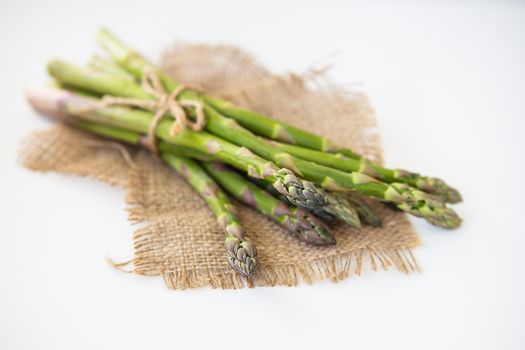 Fresh green asparagus tied with thread and lying on sacking. Healthy and wholesome food concept