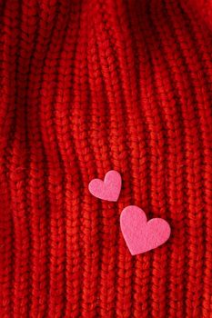 Decorative pink heart on a red knitted background, top view. Place for an inscription, vertical photo