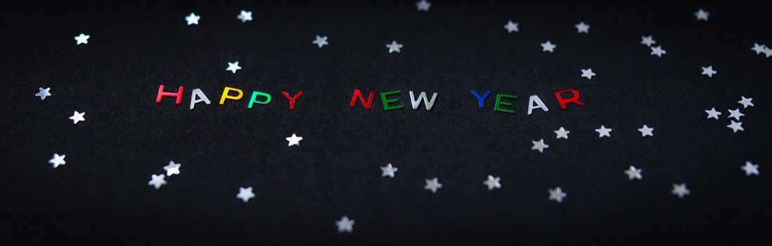 Happy new year inscription in multicolored shiny letters, together with silver stars. New Year card