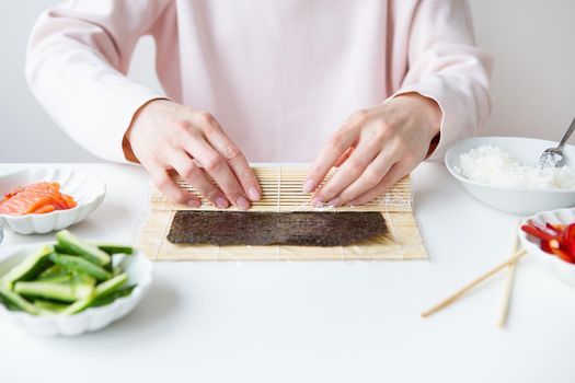 Sushi preparation process, the girl makes sushi with different flavors - fresh salmon, caviar, avocado, cucumber, ginger, rice