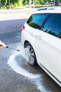 Hand washing with high pressure water in a car wash outside. A jet of foam. The concept of hand washing, self-service