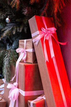 Craft gift boxes on the street near a wall made of a Christmas tree and fir. red neon shines on boxes.Christmas and new year concept. December 25